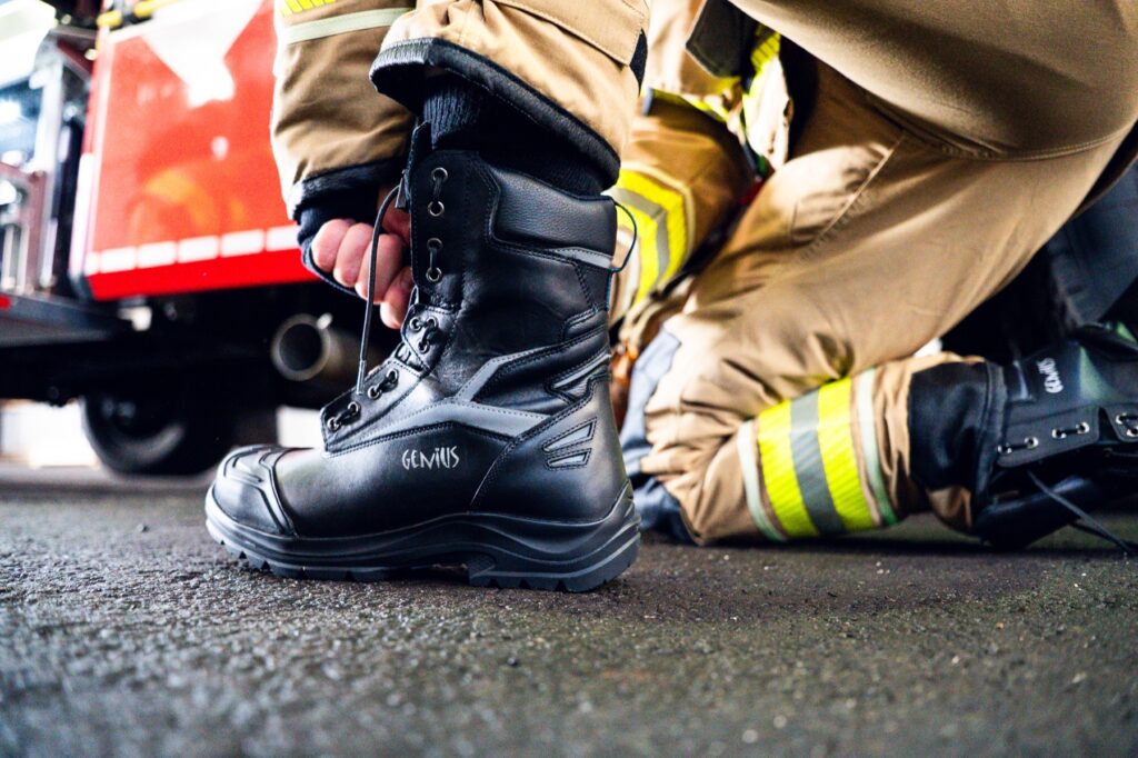 Einsatzkraft schnürt einen Genius-Feuerwehrstiefel vor dem Löschfahrzeug